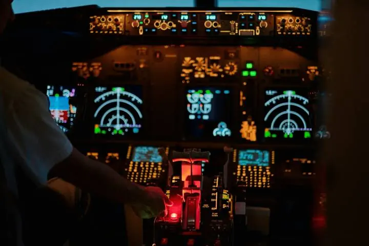 A pilot's hand on the controls in an airliner cockpit at night