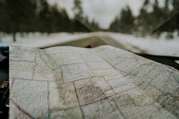 A paper road map spread across a car dashboard