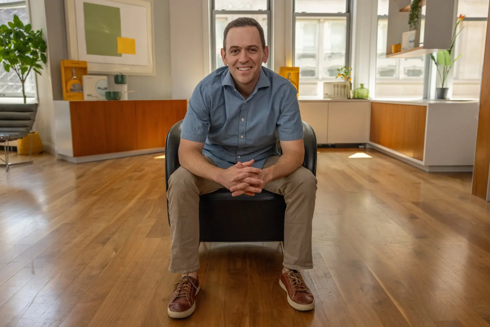 A man seated in a bright, open office